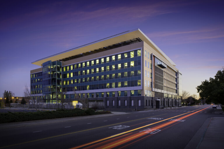 Modern glass office building at dusk with light trails on an empty street