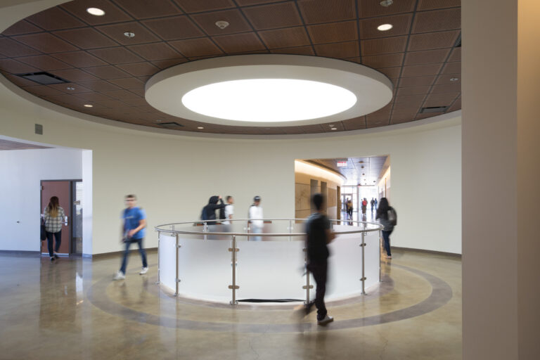 Modern lobby with a circular skylight, round railing, and blurred people walking through