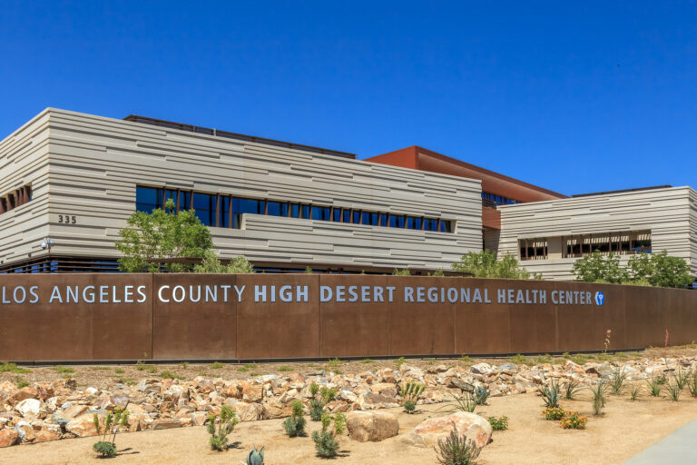 Los Angeles County High Desert Regional Health Center building with a sign in front under a clear blue sky