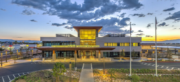 Modern health center building at sunset with glowing glass entrance and cloudy blue sky