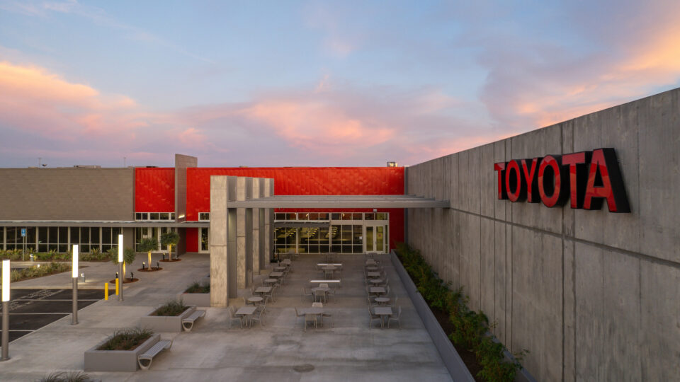 Modern Toyota building courtyard with outdoor tables, concrete walls, and a colorful sunset sky