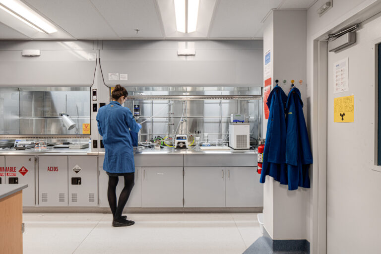 Scientist in a lab coat works at a laboratory bench inside a clean, brightly lit research lab