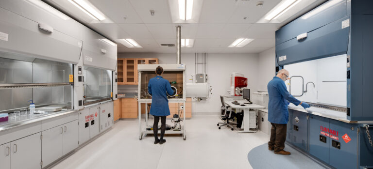 Scientists working in a modern lab with safety cabinets and a central glovebox enclosure