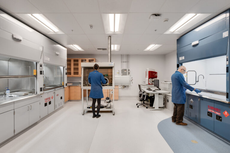 Scientists working in a modern lab with safety cabinets and a central glovebox enclosure
