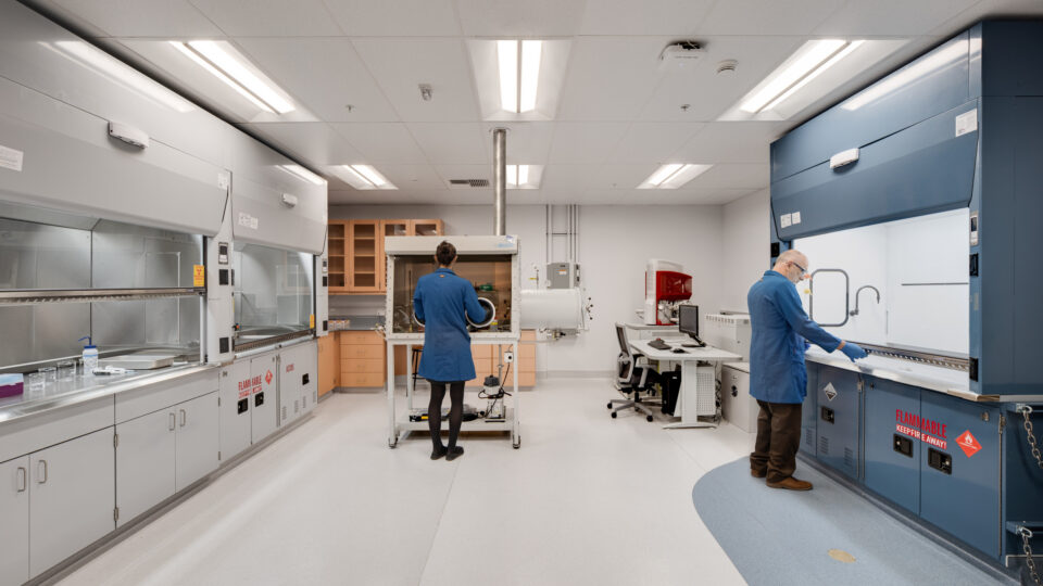 Scientists working in a modern lab with safety cabinets and a central glovebox enclosure