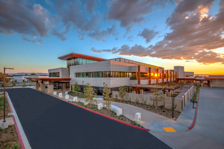 Modern office building at sunset with dramatic clouds and the sun reflecting through its windows