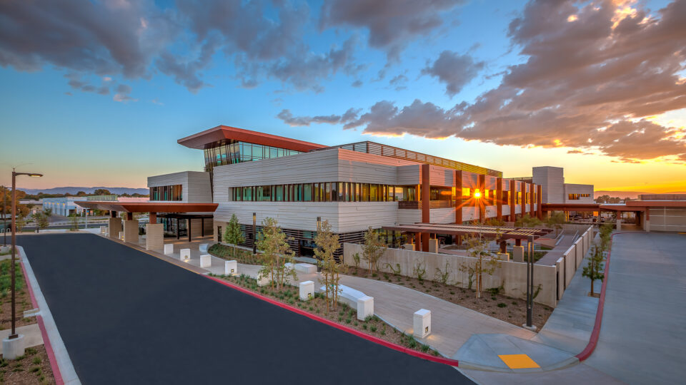 Modern office building at sunset with dramatic clouds and the sun reflecting through its windows