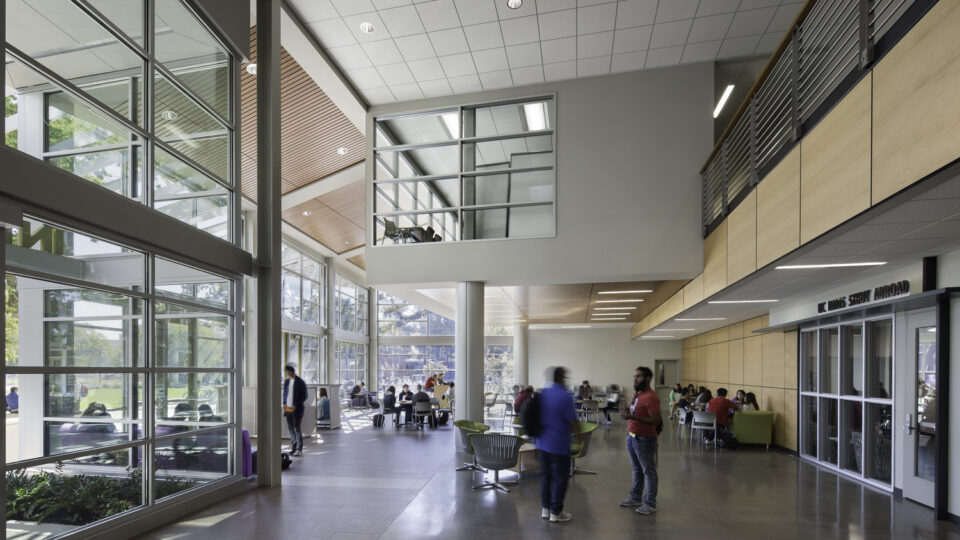 Modern university lobby with large windows, students sitting and talking, and a UC Davis Study Abroad office sign